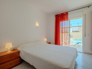 Une chambre avec un lit, des lampes de chevet, une table de chevet et une vue sur l’espace extérieur abritant une piscine.
