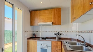 Una cocina compacta con armarios de madera, horno empotrado, estufa y lavamanos.