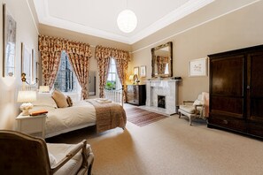 A bedroom with a large bed, a dresser, a chair, a fireplace, and a wardrobe. - 1 Bellevue Terrace - sleeps 4 guests in 2 bedrooms (Edinburgh)