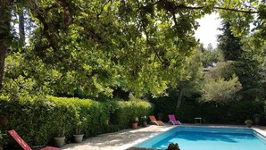 A pool area with a table and chairs, surrounded by lush greenery and trees. - Beautiful house with big garden and private pool (Mazan)