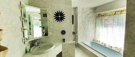 A bathroom with a sink, mirror, and bathtub.