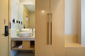 A modern bathroom with a large mirror, a white sink, and wooden cabinetry. - Huifeng Xiangxing Hotel (Liuzhou)