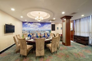 A conference room with a round table, chairs, a chandelier, a cityscape mural, and a carpeted floor. - Huifeng Xiangxing Hotel (Liuzhou)