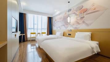 Een hotelkamer met twee bedden, een televisie, een bureau en een raam met gordijnen.