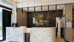 Un mostrador de recepción de hotel con diseño de mármol, un logotipo encima y una pared con un diseño oscuro y estampado.