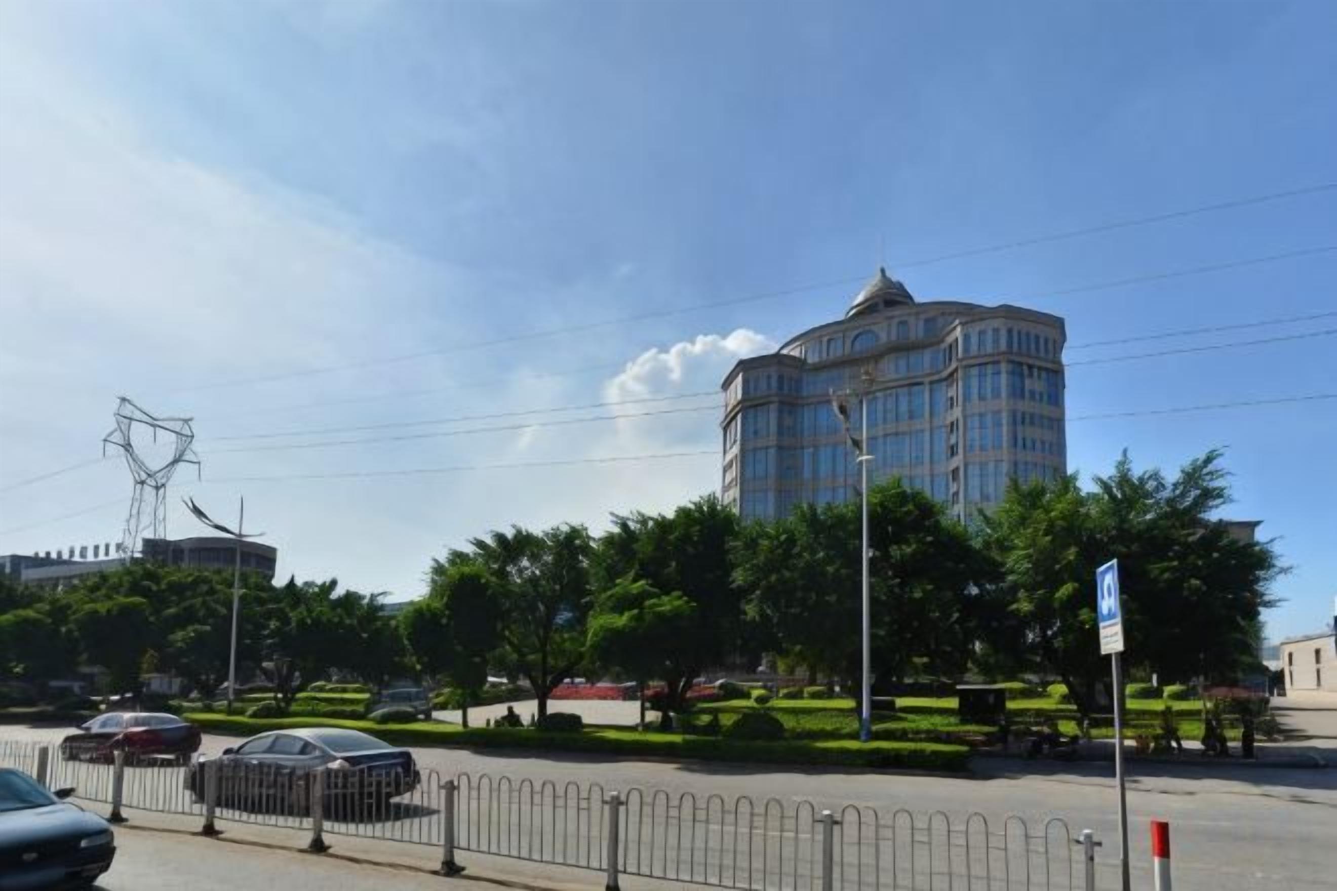 A multi-story building with a dome, surrounded by trees and a fence.