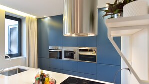 Une cuisine moderne avec des meubles bleus, des appareils en acier inoxydable et un îlot central doté d’une plaque de cuisson à induction intégrée.