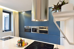 Eine moderne Küche mit blauen Schränken, Edelstahlgeräten und einer zentralen Kochinsel mit integrierter Induktionskochfläche.