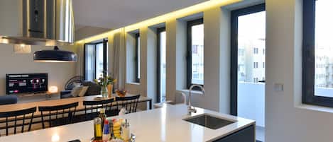 A modern kitchen with a central island, a built-in stove, and a large window providing natural light.