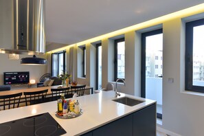 A modern kitchen with a central island, a built-in stove, and a large window providing natural light.