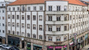 Un immeuble à plusieurs étages, doté d’un toit recouvert de tuiles rouges, qui abrite un café au rez-de-chaussée et dont la devanture est bien visible.