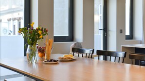 Une table à manger ornée d’un vase de fleurs, de plats remplis de nourriture et d’un luminaire suspendu.