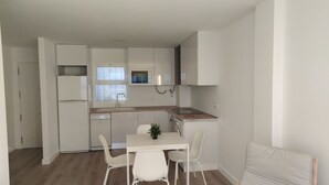 A compact kitchen with white cabinetry, a built-in oven, and a microwave. There is a small dining area with a table and two chairs. - Rincón de la Victoria.  (Rincón de la Victoria)