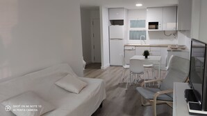 A compact living space with a sofa, a dining table with chairs, a TV, and a kitchenette. - Rincón de la Victoria.  (Rincón de la Victoria)