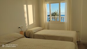 A room with two beds, a window with a view of the sea, and a small table with a basket. - Rincón de la Victoria.  (Rincón de la Victoria)