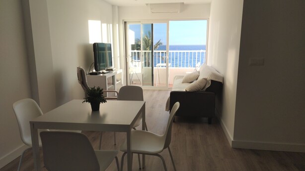 A modern living room with a balcony, a dining area with a table and chairs, and a television on a stand. - Rincón de la Victoria.  (Rincón de la Victoria)