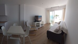 A modern hotel room with a kitchenette, a dining area, a TV on a stand, a bed, and a balcony with a view of the sea. - Rincón de la Victoria.  (Rincón de la Victoria)