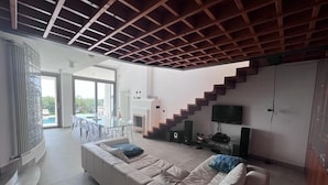 A modern living room with a white sofa, a staircase, and a TV.