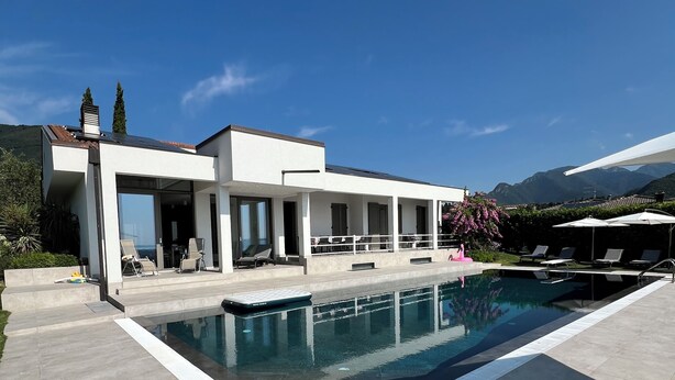 A modern house with a swimming pool, outdoor seating, and a mountain view.