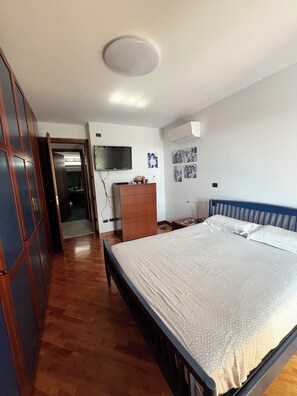 Une chambre à coucher avec un lit, une armoire en bois, une commode et un téléviseur fixé au mur.