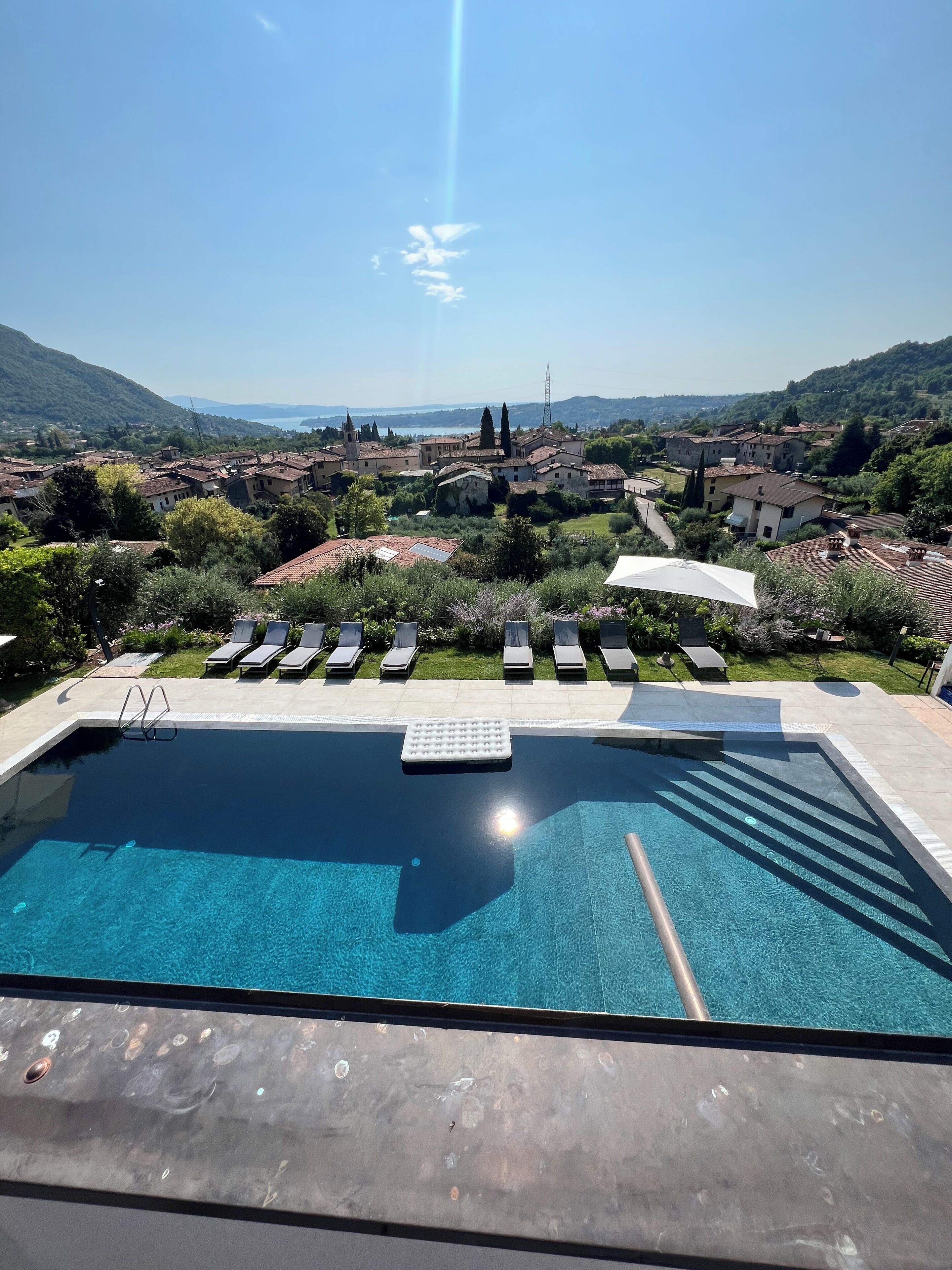 A swimming pool with lounge chairs and a view of a village.