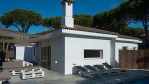 A modern villa with a swimming pool, a covered patio, and a small garden area.