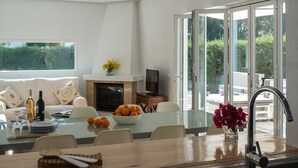 A modern kitchen with a large island, a dining area, and a living space with a TV and sofa.