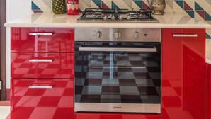 A kitchen with a gas stove, oven, and red cabinetry.