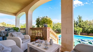 A covered patio with wicker furniture, a table with tea set, and a view of a swimming pool. - CASA MARCOS' STUNNING VILLA. (Sant Llorenç des Cardassar)