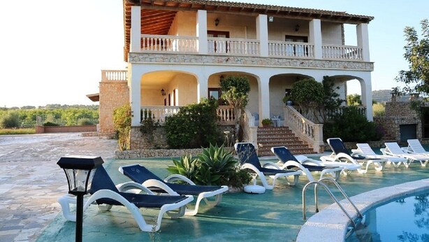 A building with a pool, lounge chairs, and a staircase leading to a balcony. - CASA MARCOS' STUNNING VILLA. (Sant Llorenç des Cardassar)