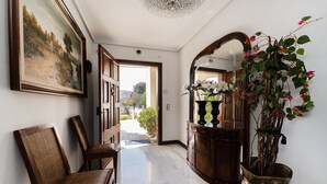A hallway with a wooden chair, a large framed painting, a potted plant, and a mirror. - CASA MARCOS' STUNNING VILLA. (Sant Llorenç des Cardassar)