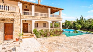 A two-story building with a stone facade, a wooden balcony, and a swimming pool with lounge chairs. - CASA MARCOS' STUNNING VILLA. (Sant Llorenç des Cardassar)