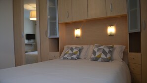 Une chambre à coucher avec un lit, deux tables de chevet et une armoire.