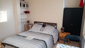 A neatly arranged bedroom with a bed, bedside table, lamp, bookshelf, and a wardrobe. - rent pretty calm and pleasant studio (Bagnoles De L'orne Normandie)