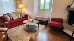 Una sala de estar acogedora con un sofá rojo, una mesa de centro redonda, un tapete estampado y una chimenea.