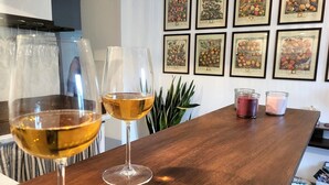 Una zona de bar con dos copas de vino, una planta en maceta e ilustraciones enmarcadas de frutas en la pared.
