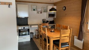 A compact kitchen with modern appliances, wooden dining table, and chairs.