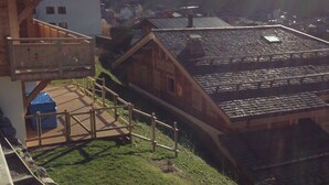 A wooden building with a balcony and a staircase leading to a green area.