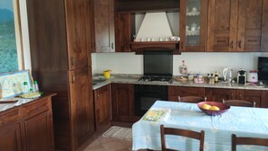 A kitchen with wooden cabinets, a stove, and a dining table with chairs. - Tranquility and spectacular views (Marciana)