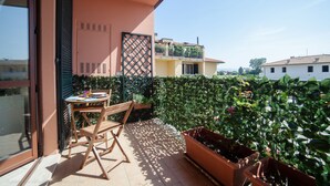 A balcony with a table and chairs, a potted plant, and a view of neighboring buildings. - Comfort and brightness in Lucca (Lucca)