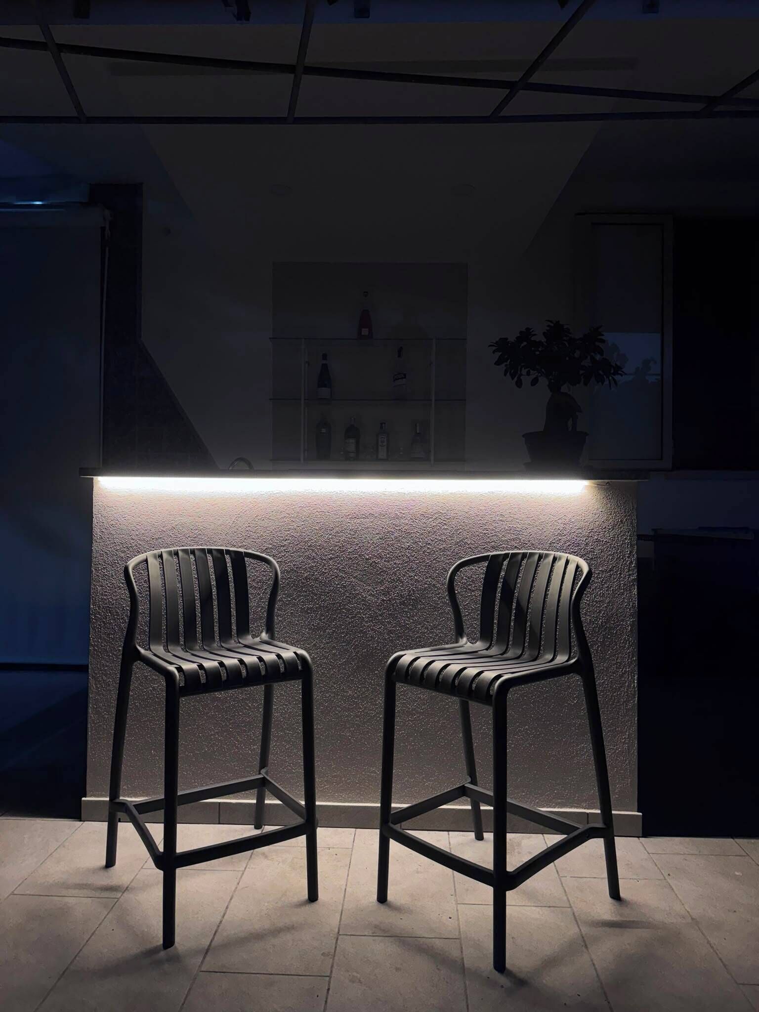 Eine Bar mit zwei schwarzen Stühlen und einer Theke.