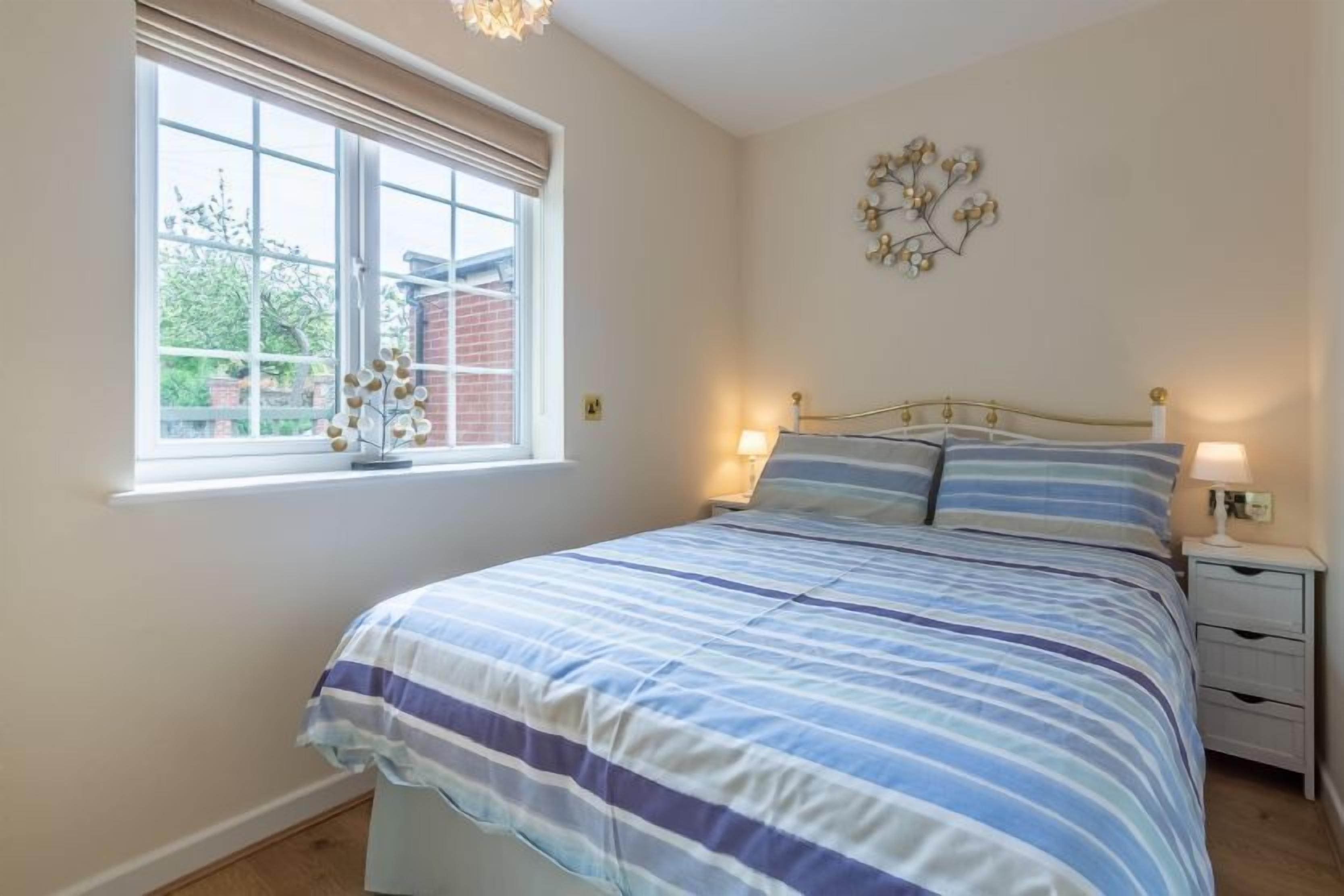 A bedroom with a bed, bedside tables, a window, and a wall decoration.