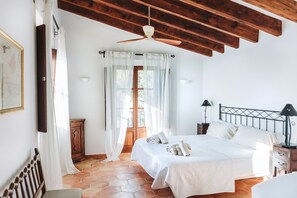 A bedroom with a bed, wooden ceiling beams, a window with curtains, a bedside table with a lamp, and a nightstand. - Villa with Private Pool and Fantastic Sea Views (Deia)