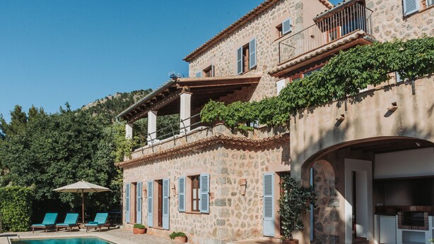 A stone villa with a swimming pool, outdoor seating, and a barbecue area.