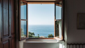 A room with an open window revealing a view of the sea.