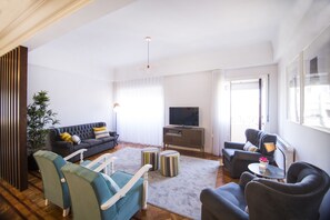 A modern living room with a sofa, armchairs, a TV, and a dining area. - Apartment for families & friends (Porto)
