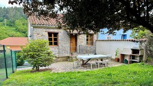 A stone house with a tiled roof, a fenced garden, and a barbecue area. - Rural Accommodations Casa Fabián, La Tenada (Pet Friendly) (Castrillón)