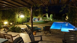 An outdoor pool area with lounge chairs and tables, surrounded by greenery and under a pergola. - Luxury Villa With Private Pool, Landscaped Garden And Sea Views (Pissouri Bay)
