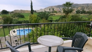 A balcony with a pool, two chairs, and a table. - Luxury Villa With Private Pool, Landscaped Garden And Sea Views (Pissouri Bay)
