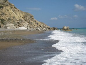 A beach with rocky cliffs and calm waves.
